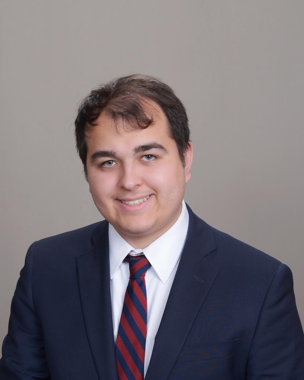 sebastian Garcia Lavin headshot wearing a blue suit with navy and maroon striped tie