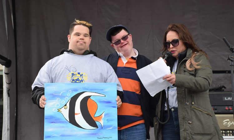 Young man holds up fish artwork.