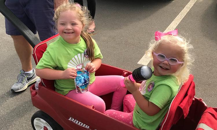 Two young girls sit in a wagon.