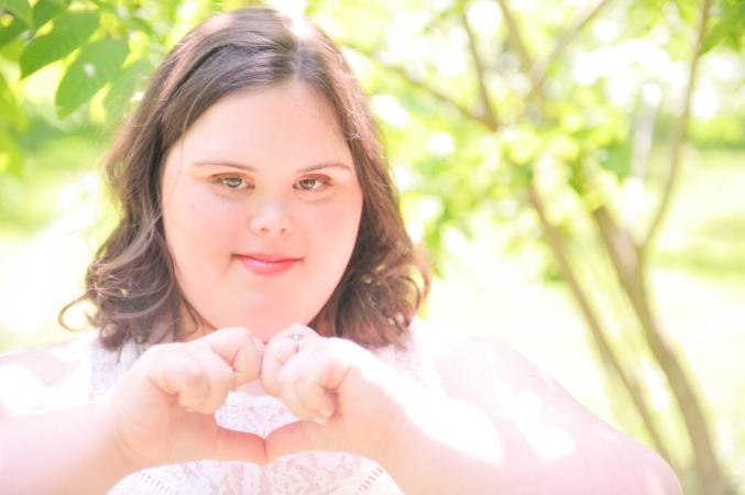 Young woman with Down syndrome making a heart with hands